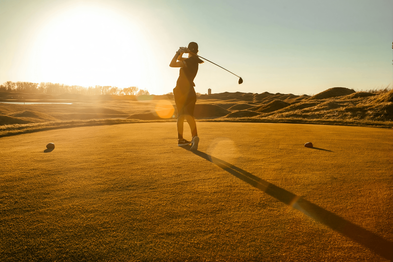 Ein Golfer bei einem flüssigen Schwung zum Sonnenuntergang – ein Symbol für mentale Klarheit und körperliche Leichtigkeit durch Akupunktur.