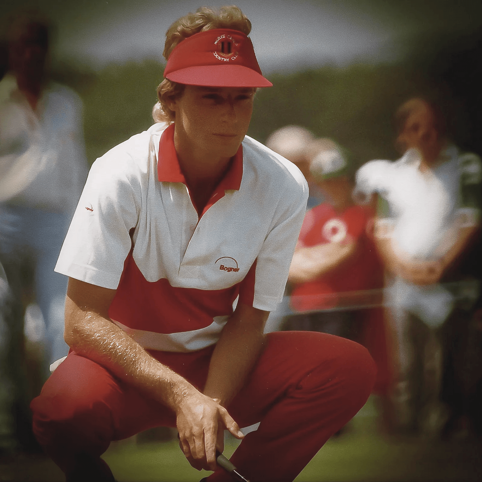 Bernhard Langer in den 1980er-Jahren mit seinem ikonischen roten Visier und Bogner-Golfbekleidung, hockend auf dem Grün bei der Analyse eines Putts. Bernhard Langers Golfschwung, meine Analyse. 